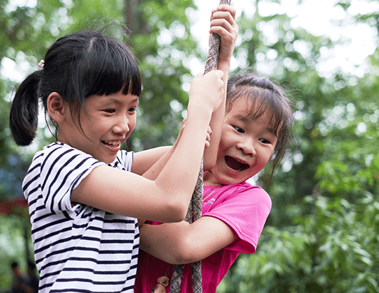 Two children playing on a rope swing