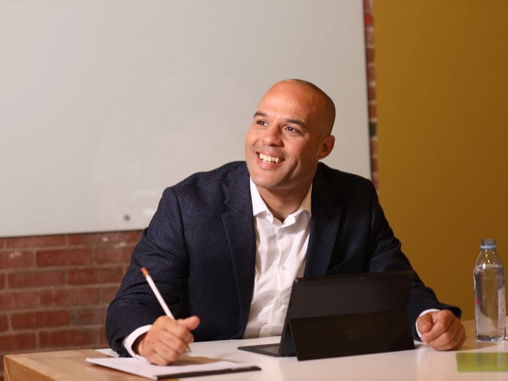 Man smiling while writing something down. 