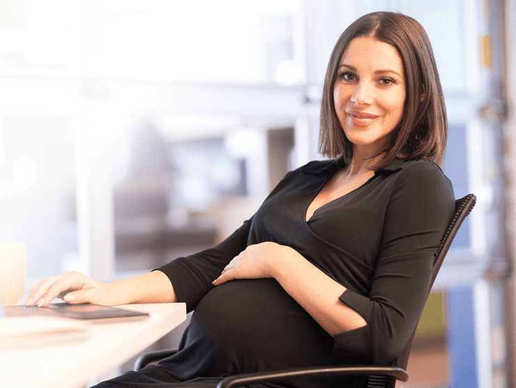 A pregnant woman sitting in her office