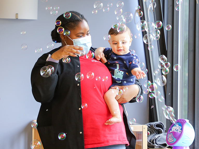 daycare teacher with baby playing with bubbles