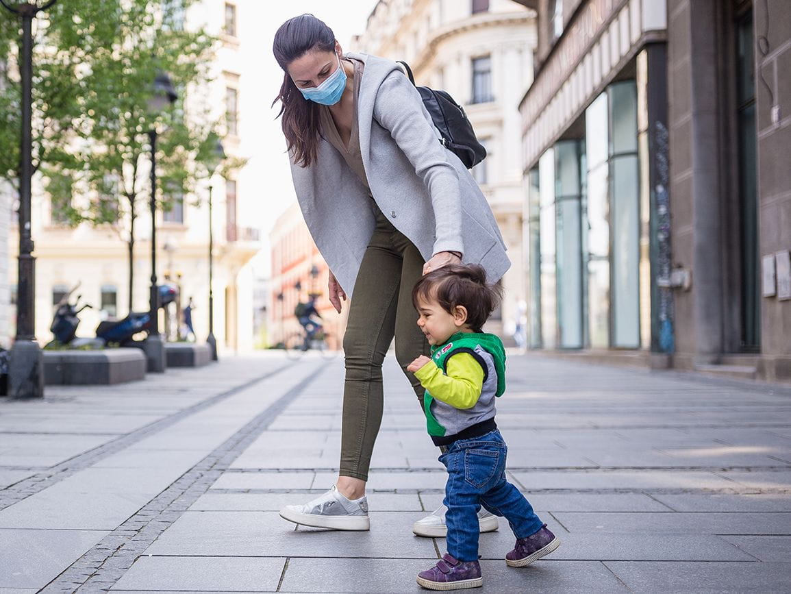mother with her child on street wearing mask