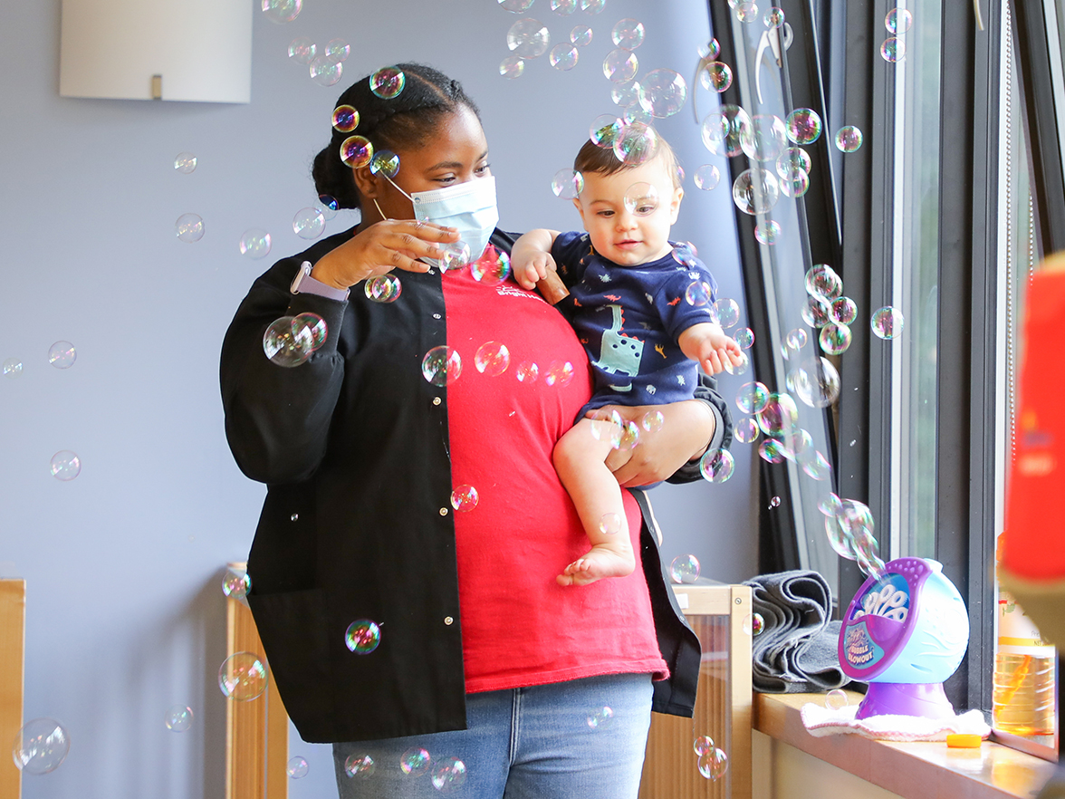 bright horizons teacher with infant playing with bubbles