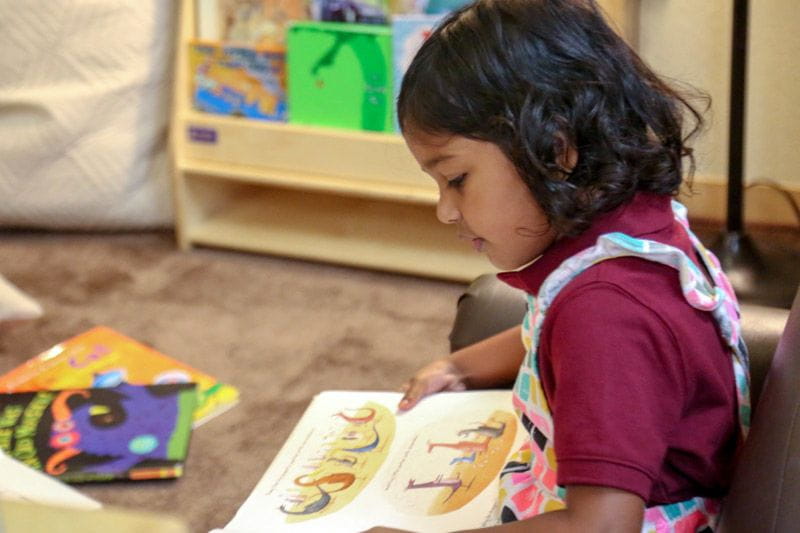 Preschool girl reading at a child care center