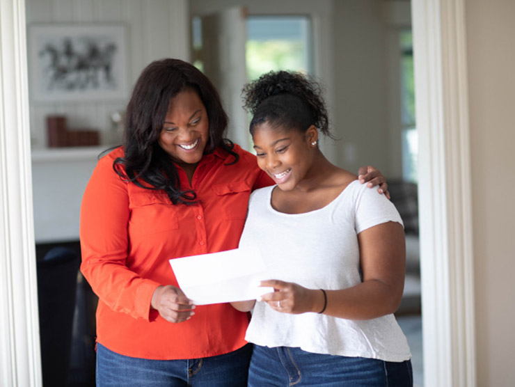 Working mom and daughter looking at college acceptance letter