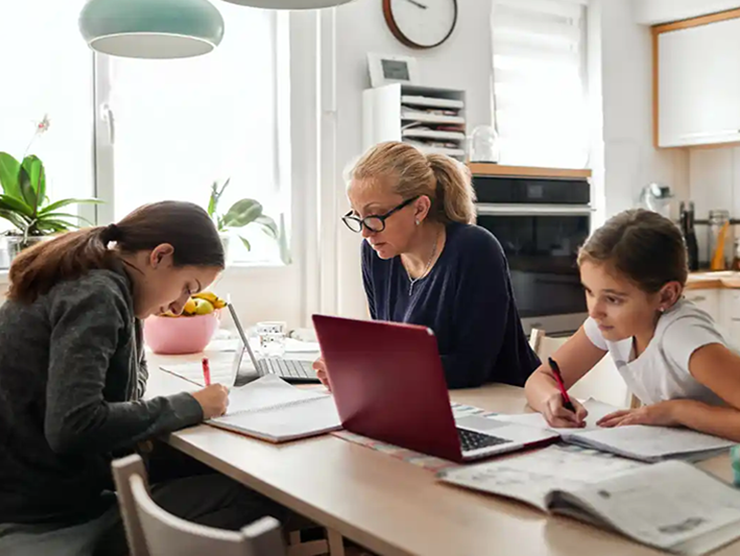 Mom working from home while helping her children with homework