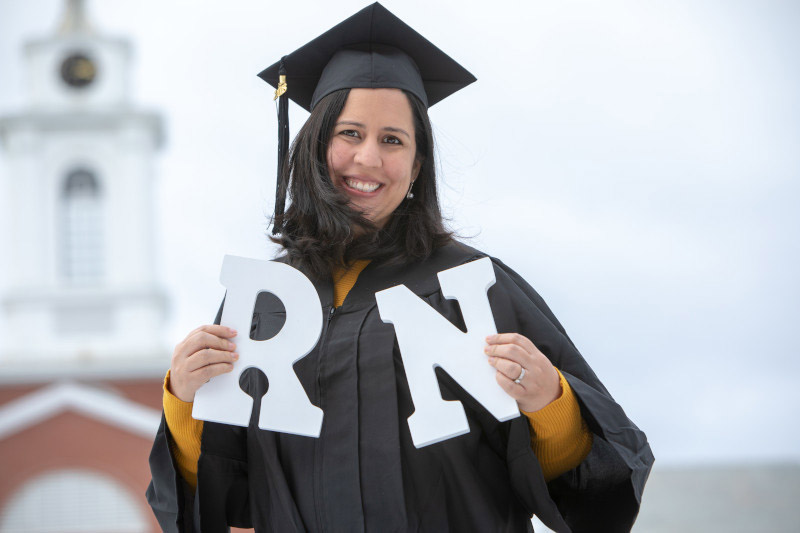 Nurse at her graduation holding the letters 'RN'
