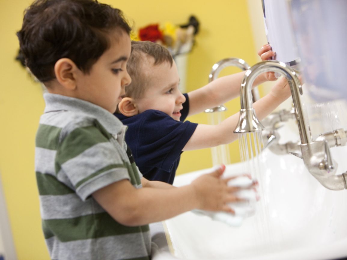 Two toddler boys washing hands at a sink