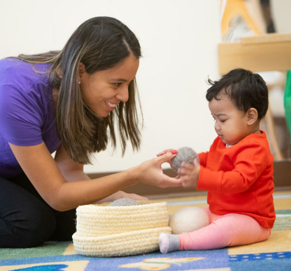 A daycare teacher focuses on a young child's learning and development at a local preschool
