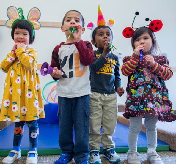 Young children playing with hats and instruments at daycare