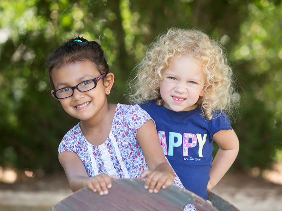 Two preschool girls smiling outside at summer camp