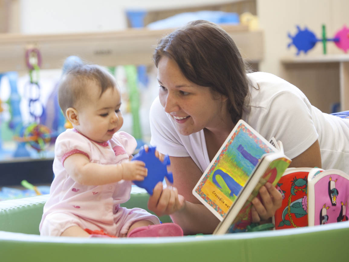 Teacher reading a book to an infant