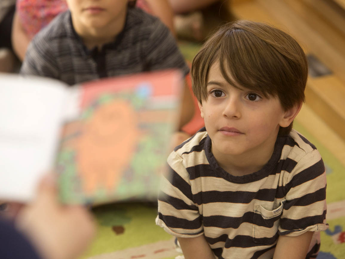 Pre-kingergarten boy listening to the teacher read aloud