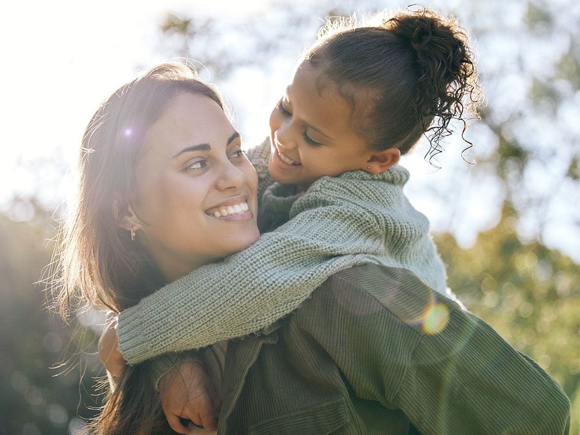 Hispanic mother and daughter outside smiling