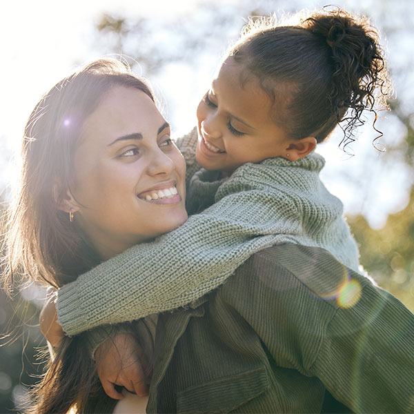 Hispanic mother and daughter smiling at daycare