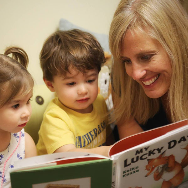 Teacher reading to a toddler boy and girl