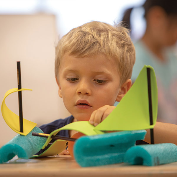 Boy making a toy boat in the preschool program at Bright Horizons