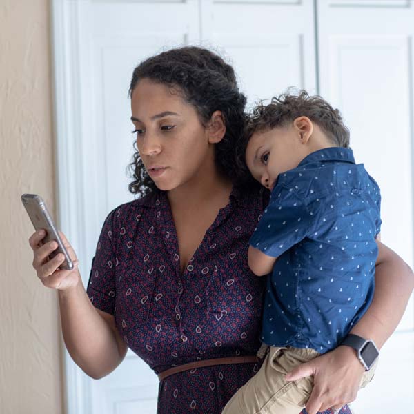 Bright Horizons Modern Family Index Mother Holding Tired Child on Smartphone