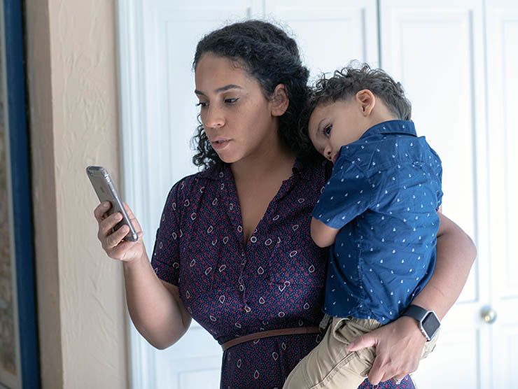 Mom looking at phone while holding child