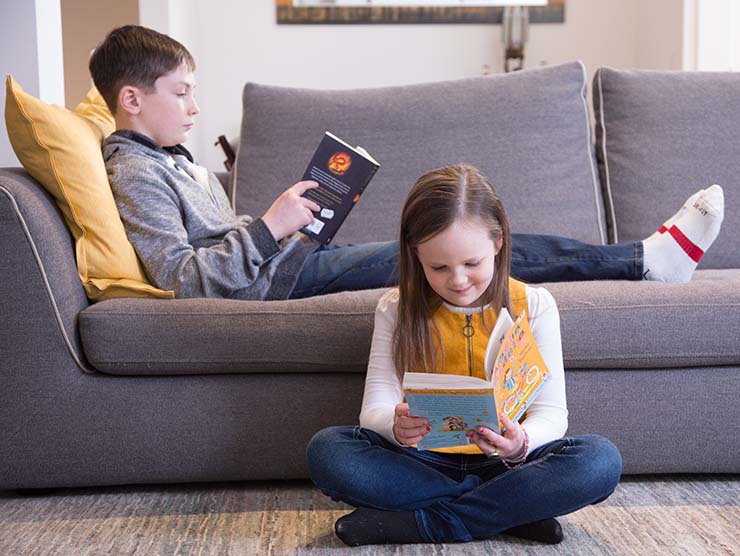 Siblings reading at home on the couch