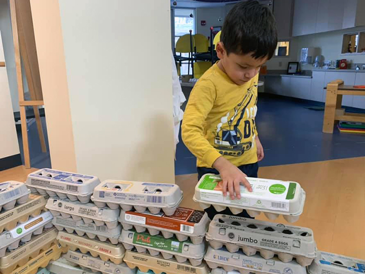 Child building house made out of egg cartons