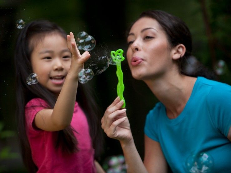 babysitter blowing bubbles with child 