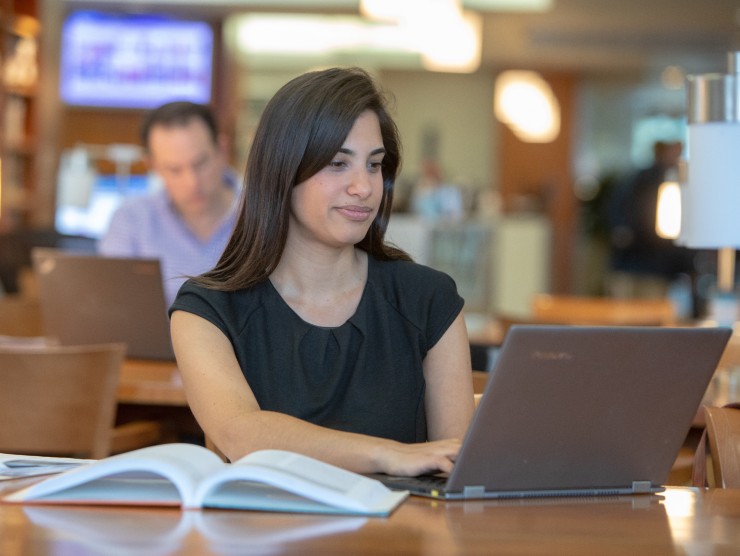 woman sitting at tale with laptop and books