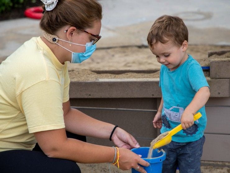 teacher and child playing with sand