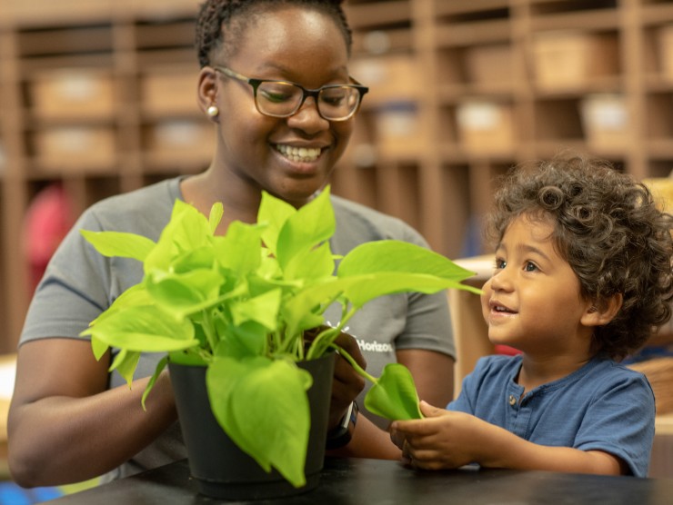 child and teacher looking at plant 