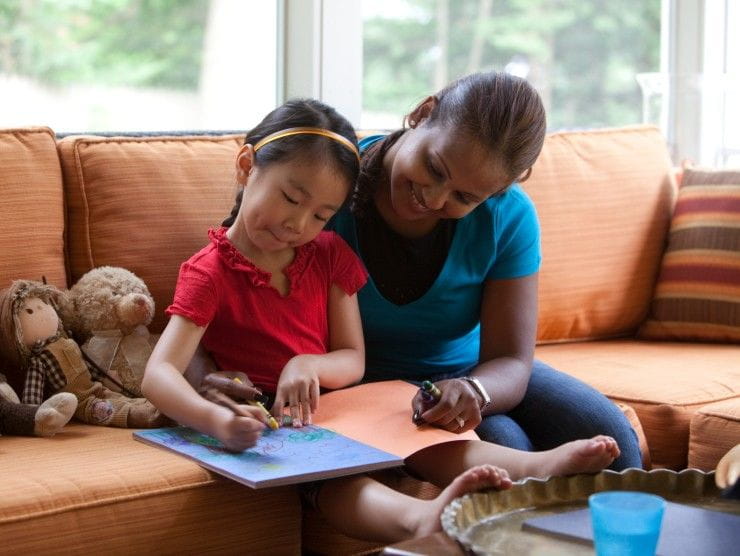 babysitter sitting with child reading book 
