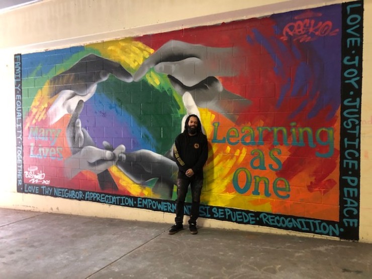 artist in front of mural 