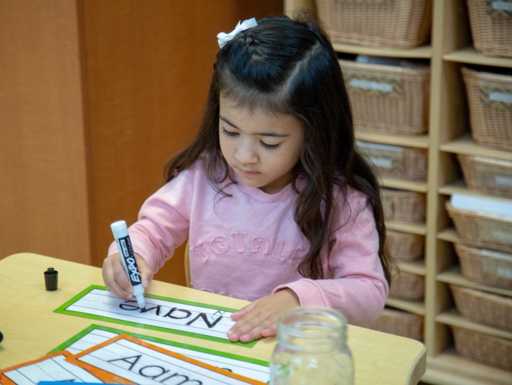 child sitting at table writing name 