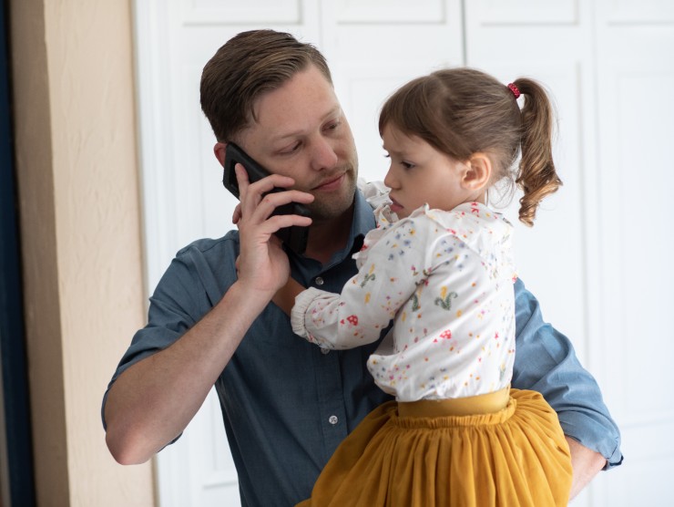 dad on phone holding daughter 