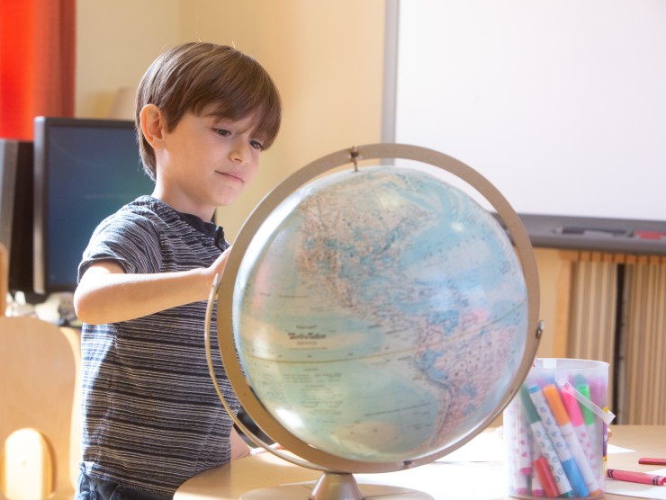 child looking at globe 