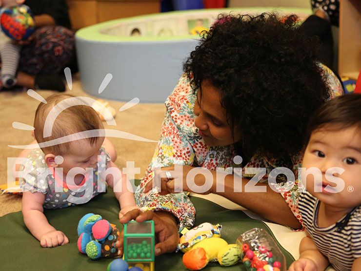Bright Horizons teacher sitting with infants during tummy time