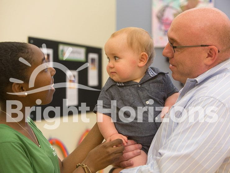 Dad holding his infant son while talking to the teacher