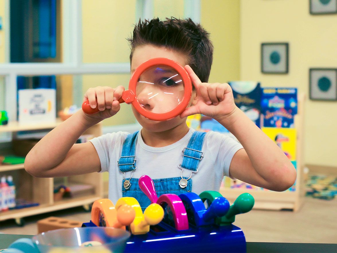 Young child in daycare learns sensory skills with magnifying glass