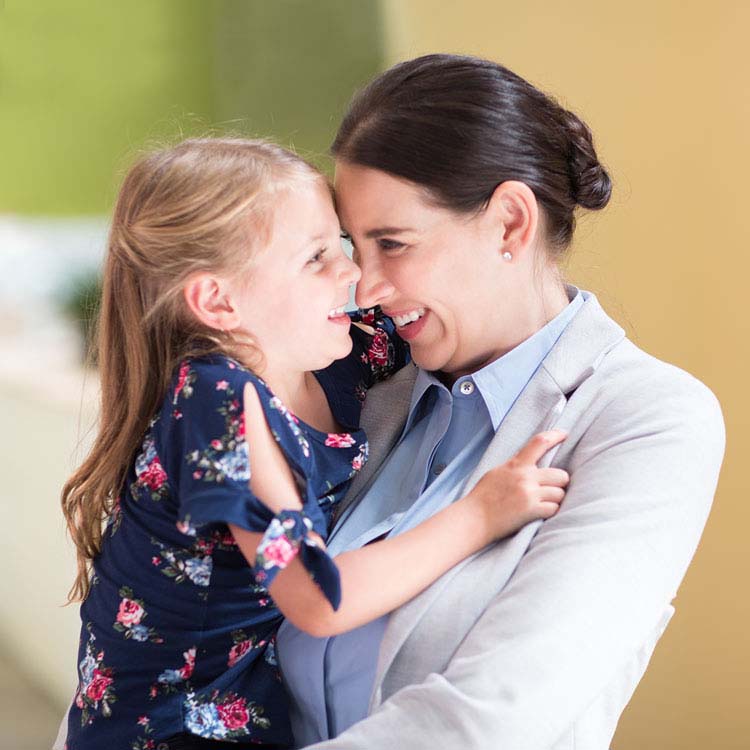 Working mom hugging preschool-aged daughter