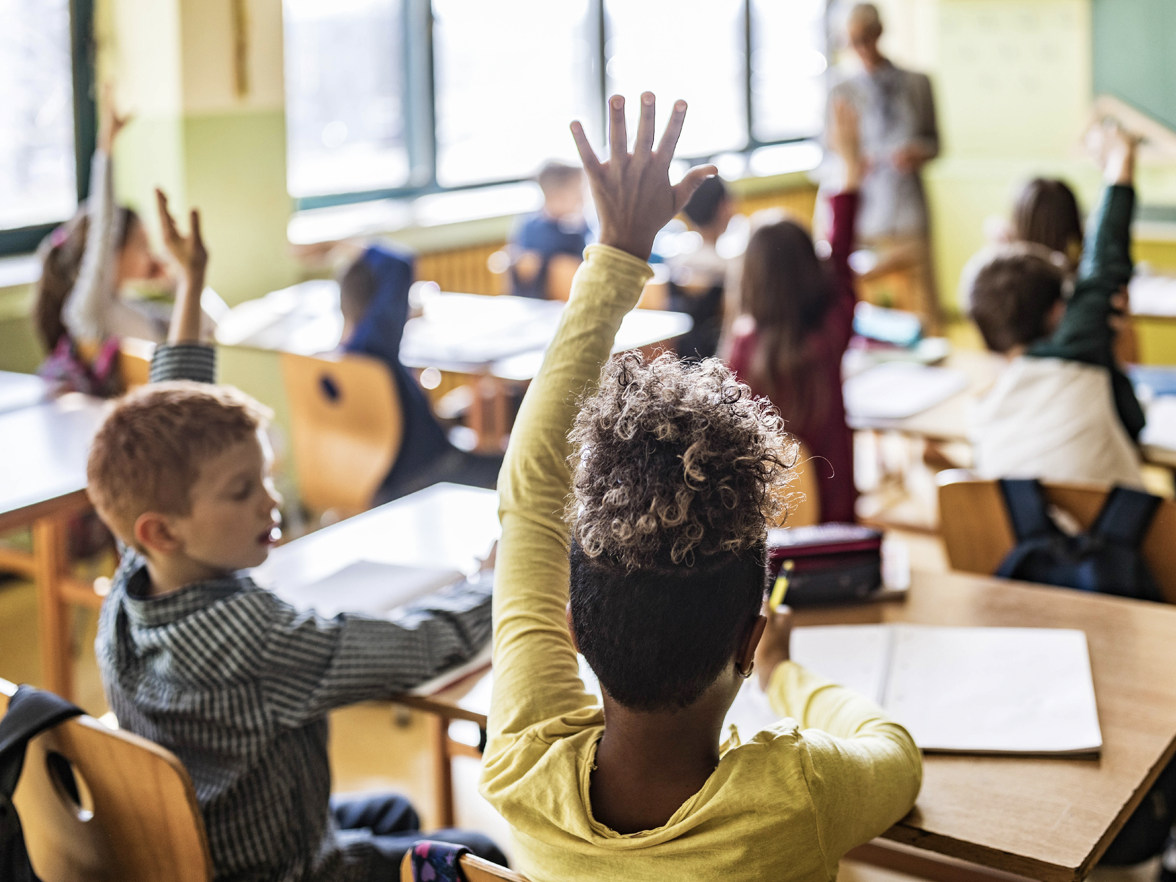 classroom of kids raising their hands