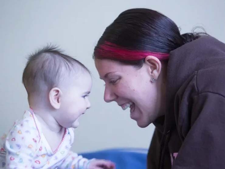 A mother and baby smile at each other, learning social emotional skills at daycare