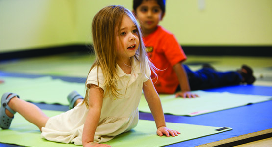 Young children practice yoga poses at daycare