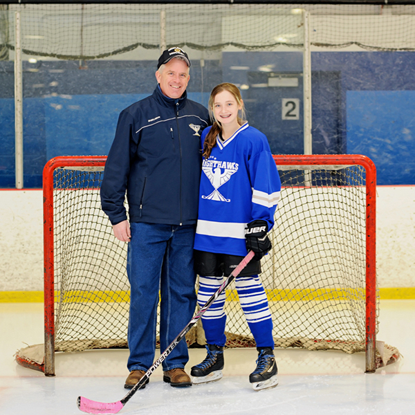 Patrick Donovan, Senior Vice President, Emerging Services, standing with his daughter playing hockey in front of a goal