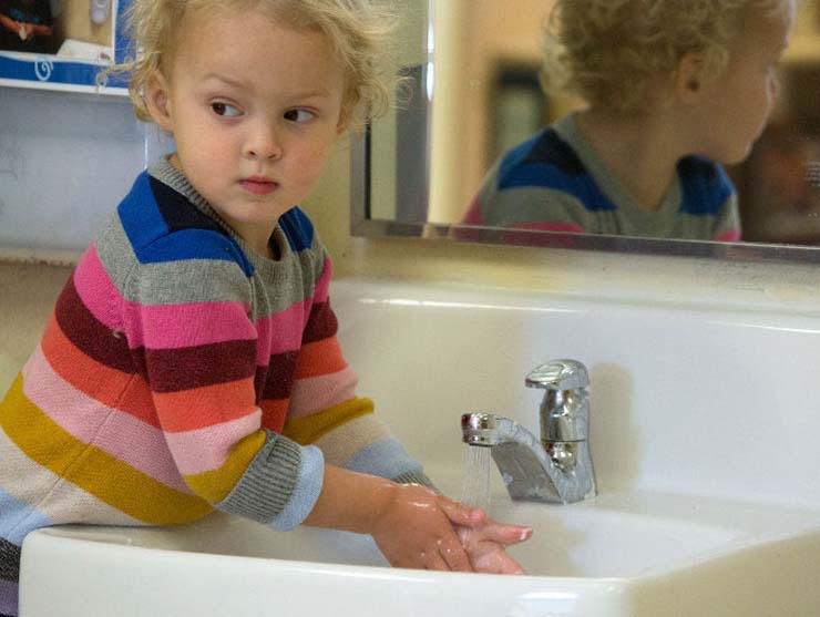 girl washing hands to stay healthy and safe at Bright Horizons child care