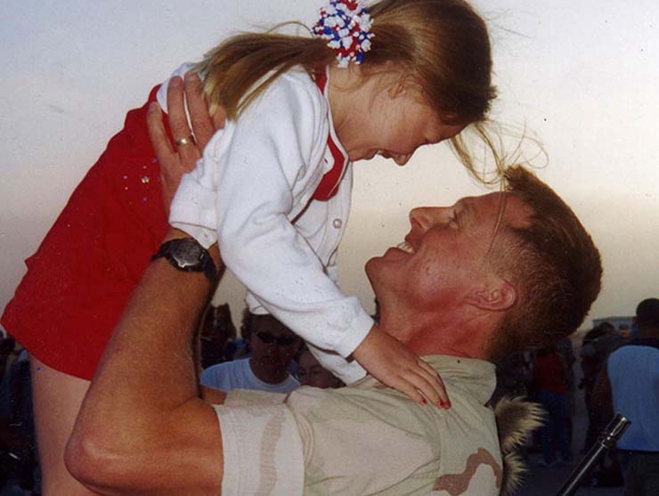 preschool girl hugging veteran back from deployment