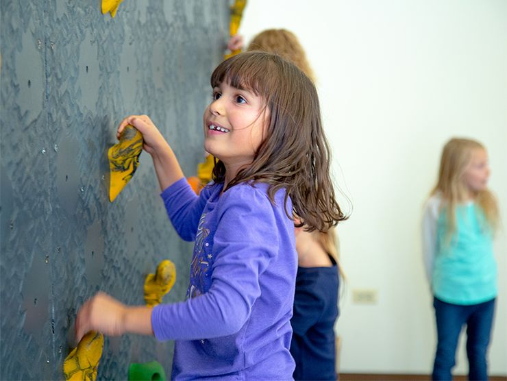 young girls confidently climbing a rock wall
