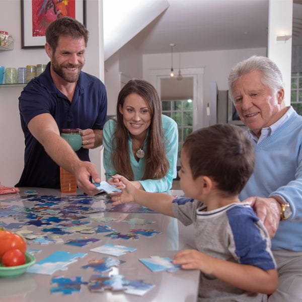 Parents with young child and grandfather doing a puzzle together