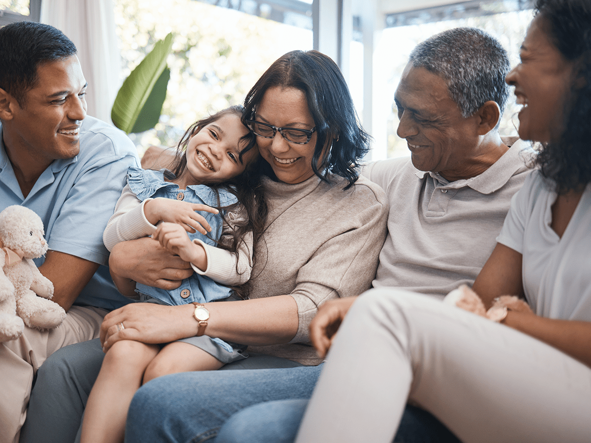 Family of three generations sitting on a couch smiling