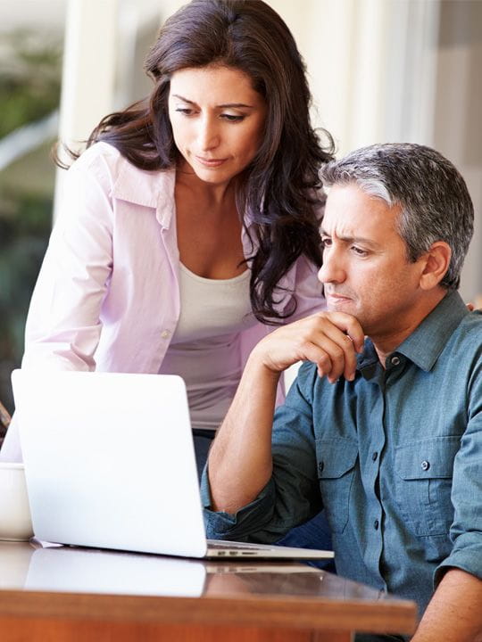Two people reviewing their education expenses on a computer.