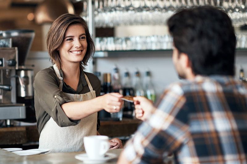 Female barista handing a customer his credit card back