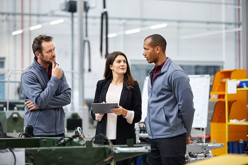 Three people talking in a factory