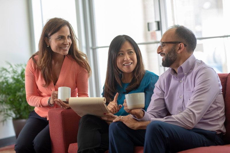 Three diverse co-workers happily collaborating at work